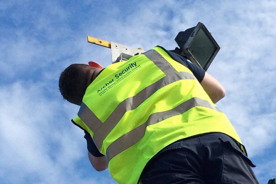 Engineer in Archer Security hi-vis fitting a floodlight on a pole